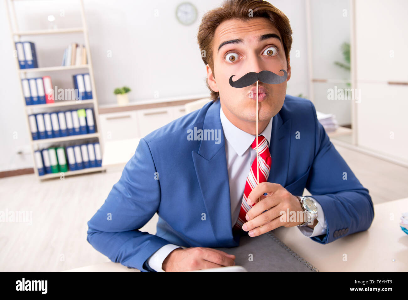 Funny bisinessman con baffi finti in ufficio Foto Stock