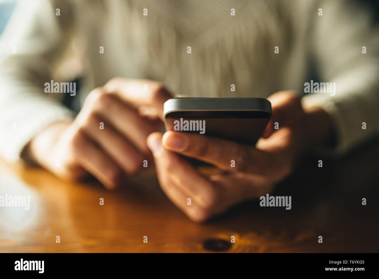 Donna che utilizza smartphone sul tavolo di legno al cafe'. Close-up immagine con reti sociali di concetto Foto Stock