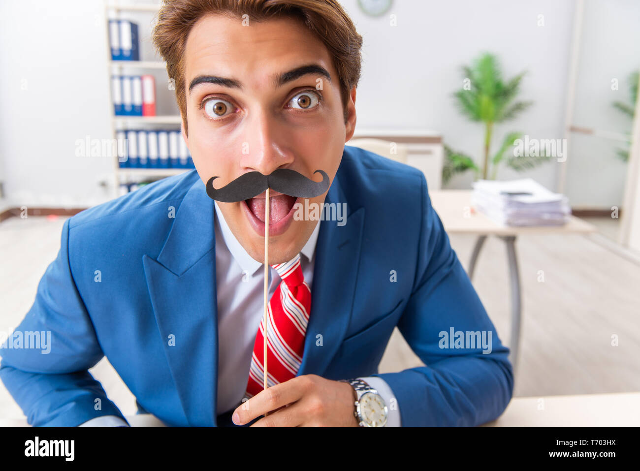 Funny bisinessman con baffi finti in ufficio Foto Stock