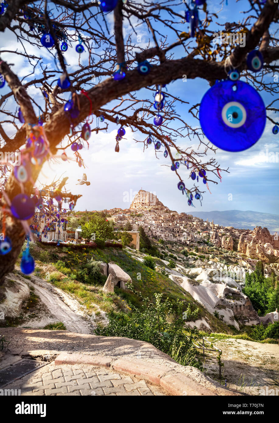 Il Castello di Uchisar al tramonto e albero con tradizionali turchi occhi amuleti in Cappadocia Foto Stock