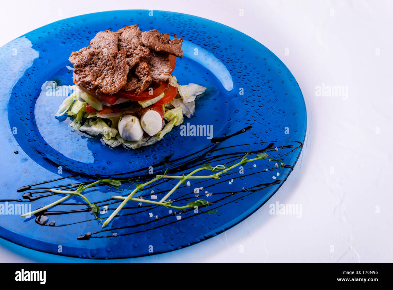 Il cibo italiano su sfondo bianco. Mozzarella, di foglie di basilico fresco, pomodoro, olio d'oliva, carne sulla piastra. Caprese salat ingredienti. Vista dall'alto. Foto Stock