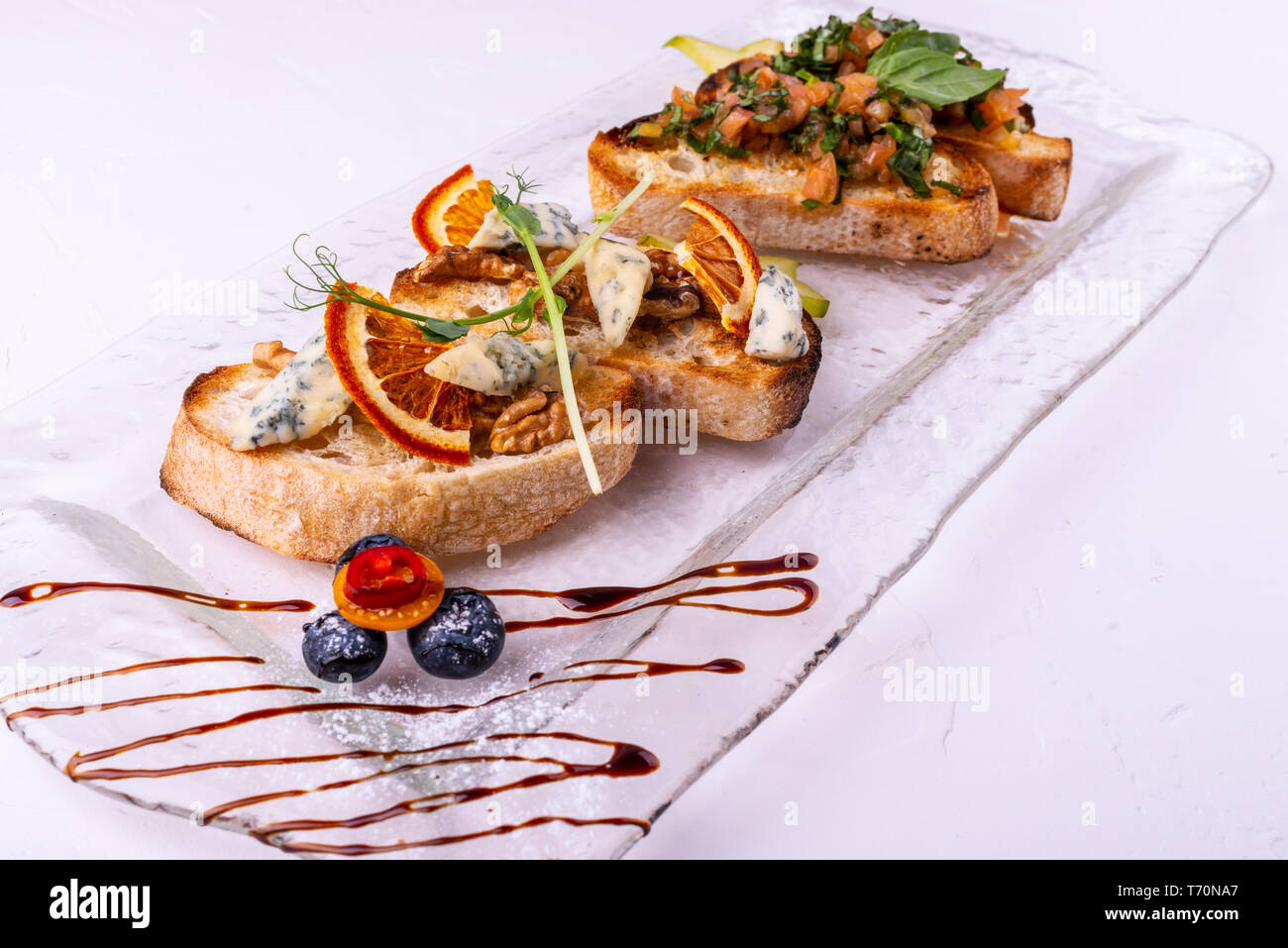 Antipasto bruschetta con formaggio, miele, noci e asciugare le fette di colore arancione su sfondo bianco. Close-up. Foto Stock