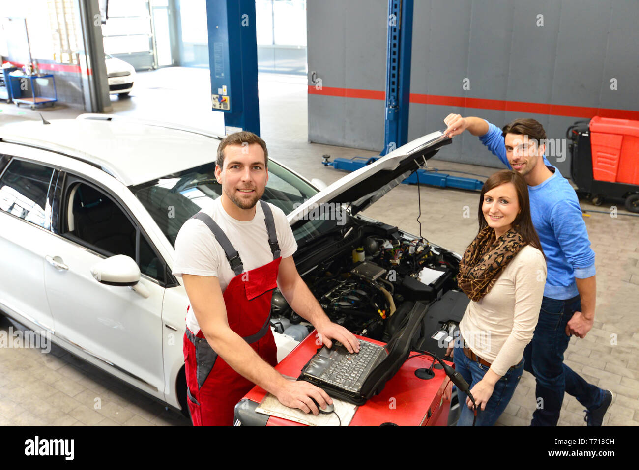 Assistenza clienti in un garage - meccanico e il cliente discutere la riparazione di un veicolo Foto Stock