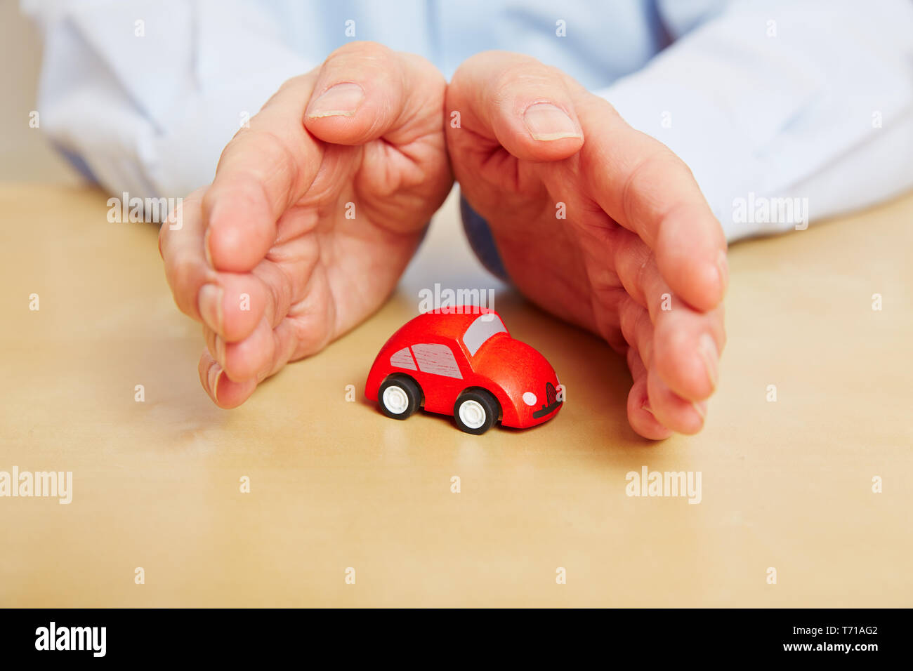 Proteggere le mani un po' auto rossa come un simbolo per auto di assicurazione Foto Stock