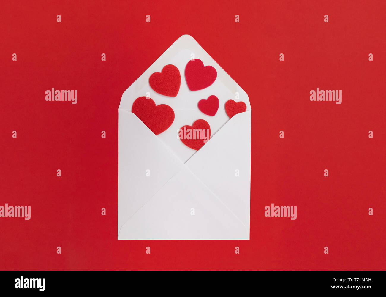 Lettera d'amore concetto. Busta bianca con cuori fuoriuscita, con uno sfondo rosso. Foto Stock