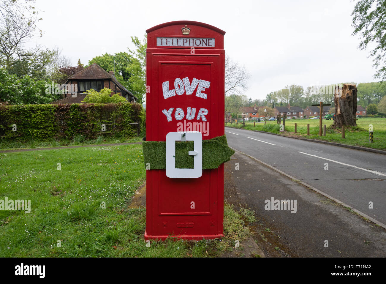 Telefono rosso scatola (casella telefono) con il messaggio di amore la vostra cintura verde, una protesta circa la politica locale che minacciano la cintura verde vicino a Guildford Regno Unito Foto Stock