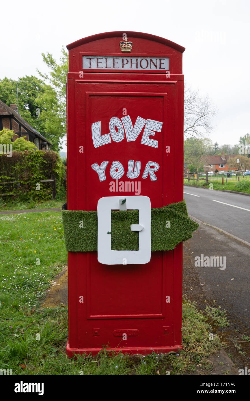 Telefono rosso scatola (casella telefono) con il messaggio di amore la vostra cintura verde, una protesta circa la politica locale che minacciano la cintura verde vicino a Guildford Regno Unito Foto Stock