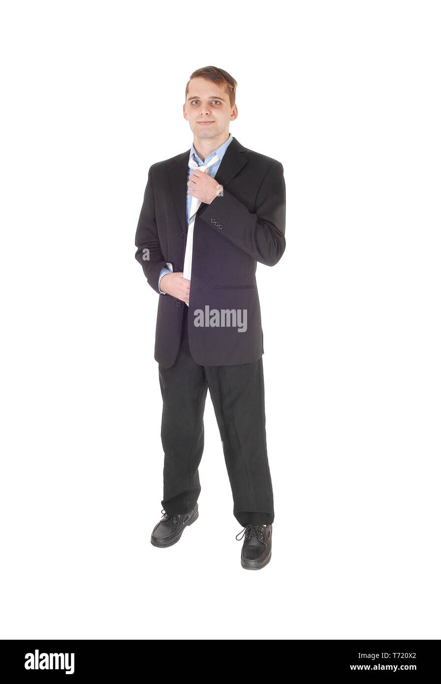 Giovane uomo in piedi in un vestito che fissa il suo tirante Foto Stock