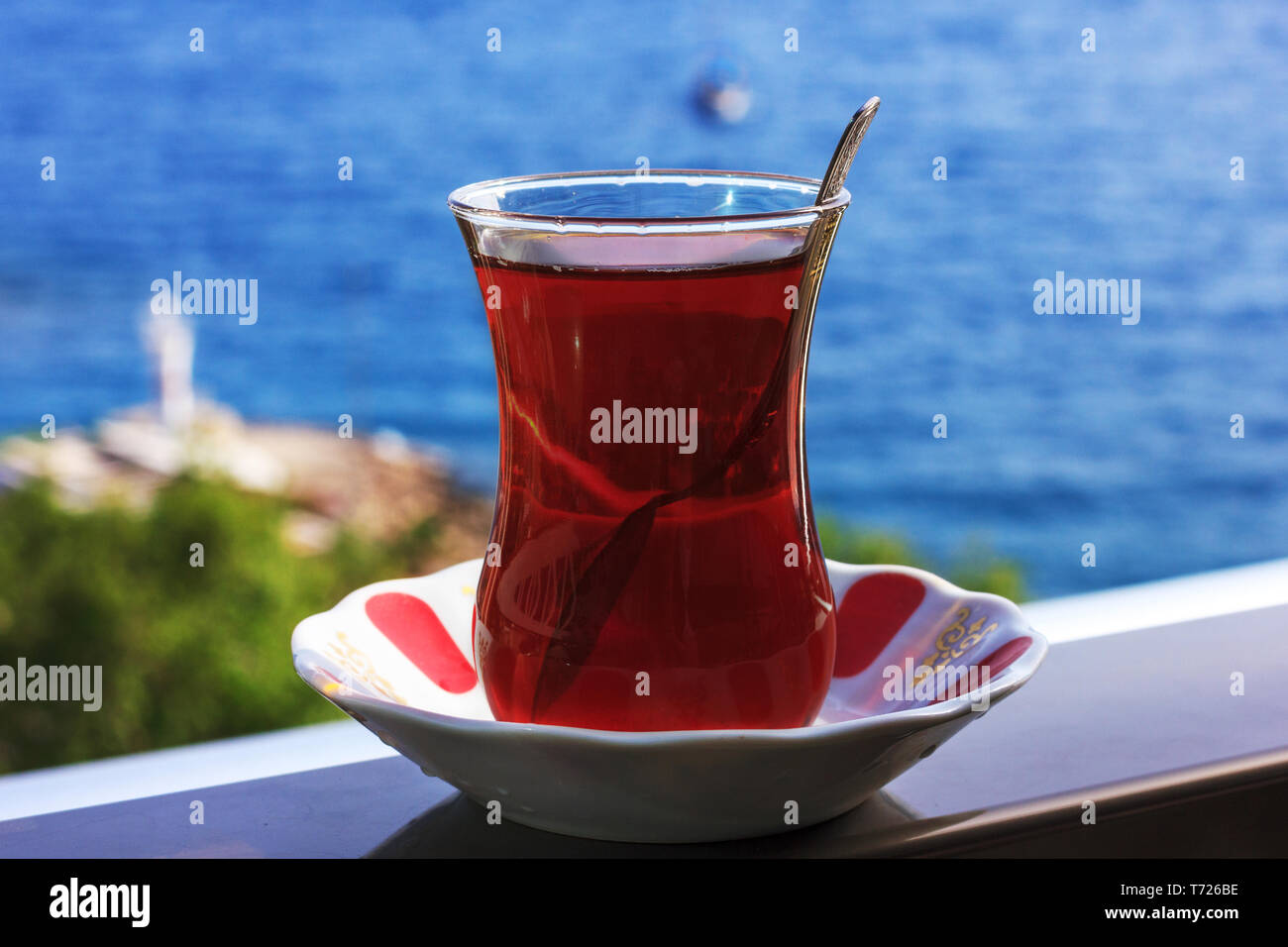 Bagno turco tè nero in vetro tradizionale sullo sfondo del blu mare Mediterraneo Foto Stock