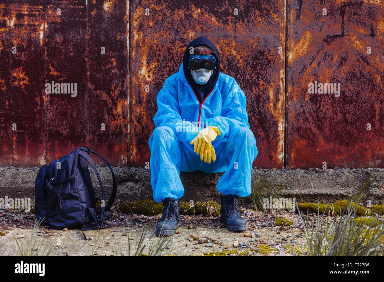 Gli uomini in blu tuta protettiva presso la vecchia fabbrica distrutta. Concetto di inquinamento ambientale e la catastrofe ecologica. Foto Stock