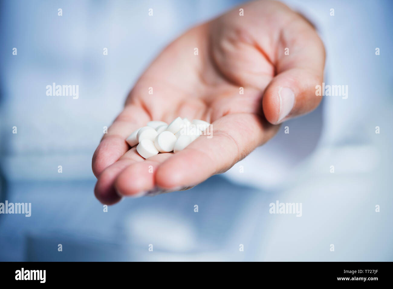 Primo piano di un medico caucasica uomo in camice bianco, dando alcune pillole per l'osservatore Foto Stock