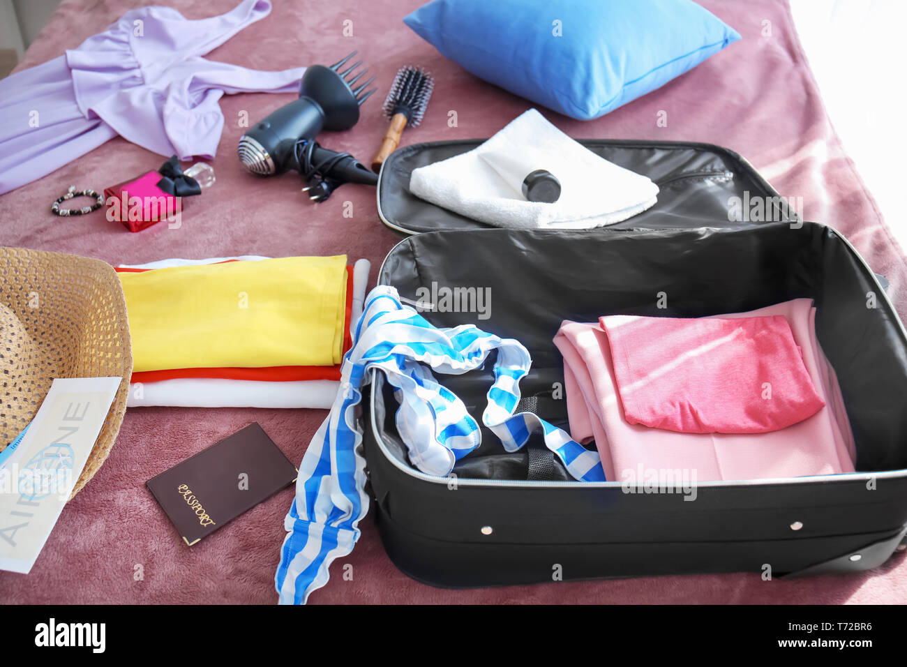 Aprire la valigia di viaggio con vestiti sul letto Foto stock - Alamy