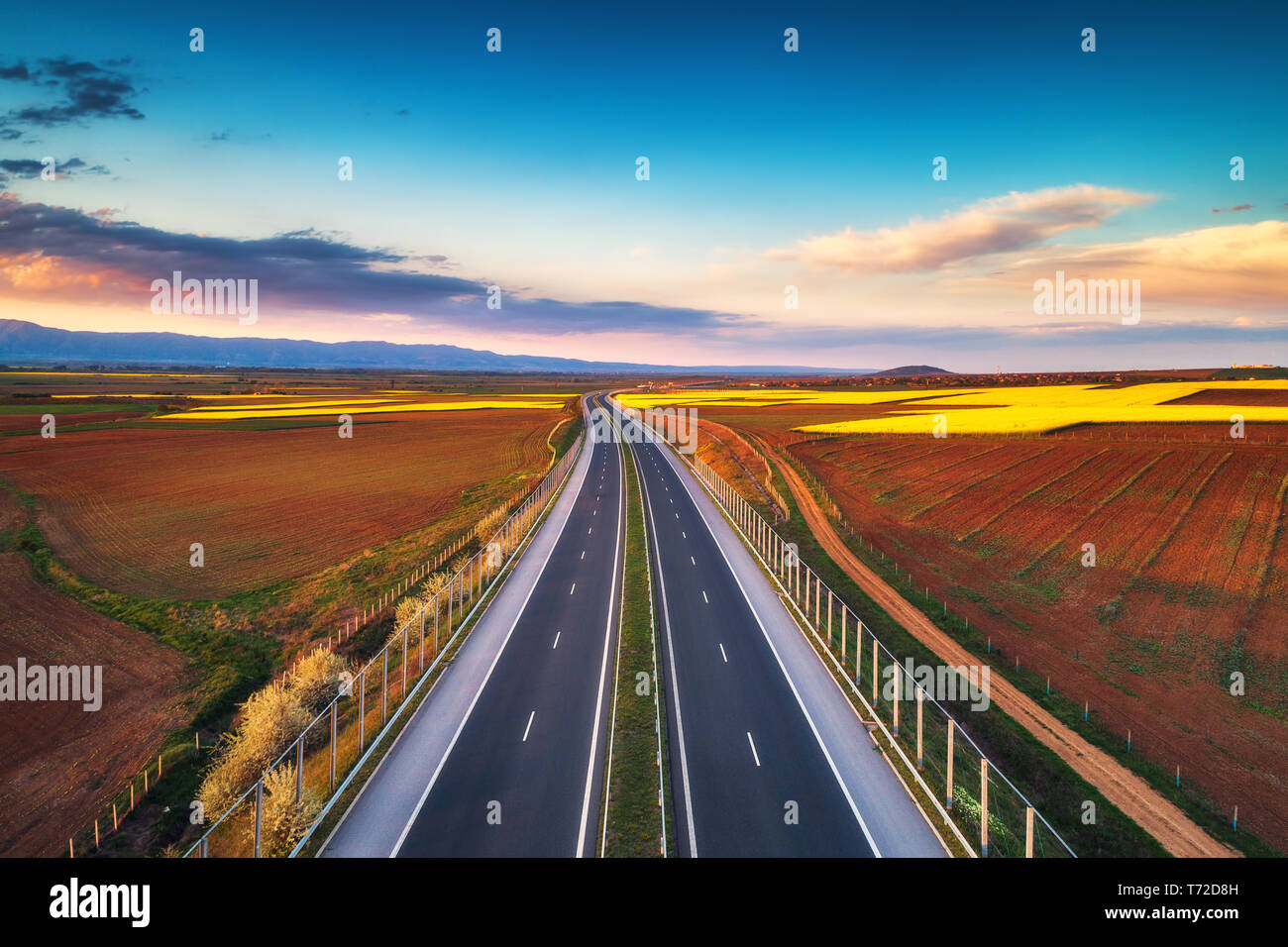 Vista aerea dell'autostrada sul tramonto. Sfondo di trasporto. Paesaggio con strada vicino a campi di campagna. Foto Stock