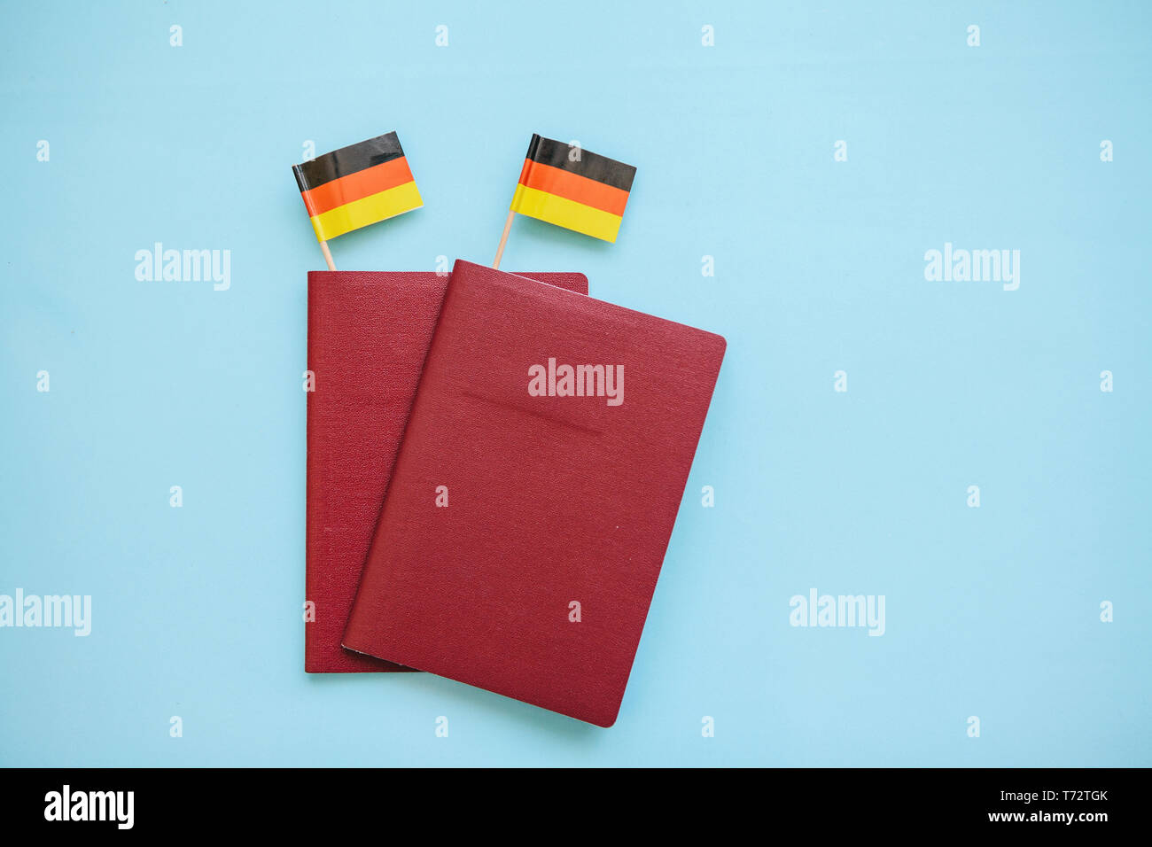 Passaporto straniero con le bandiere della Germania su uno sfondo blu. Il concetto di migrazione, di lavoro e di viaggio. Foto Stock