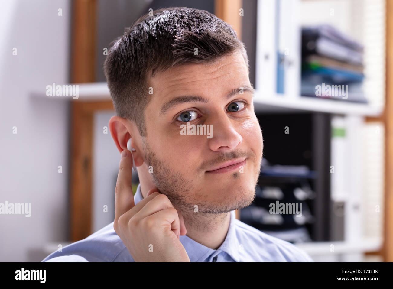 Felice giovane impreditore Indossa auricolari wireless in ufficio Foto Stock
