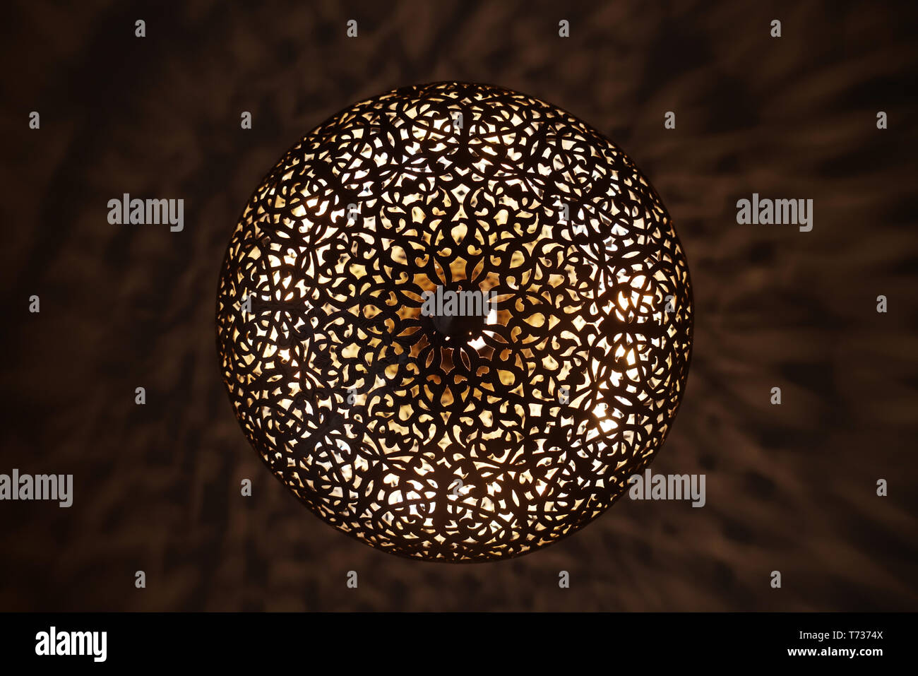 La luce è misteriosamente diffusa attraverso le fessure di fortemente ornamentale lampadario marocchino di Marrakesh che i progetti della bravura dei suoi fabbri. Foto Stock
