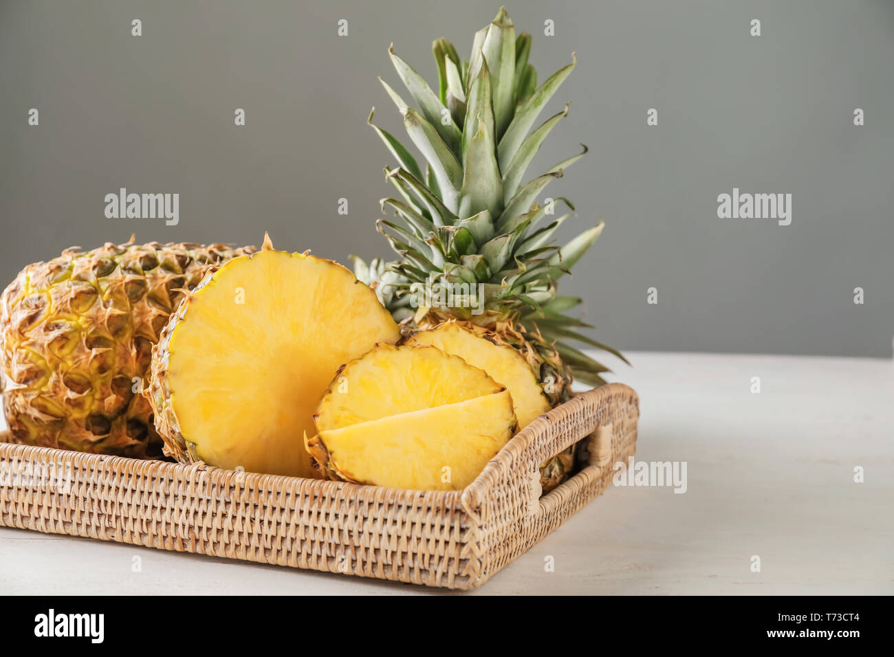 Vassoio di vimini con gustose fette di ananas sul tavolo bianco Foto Stock