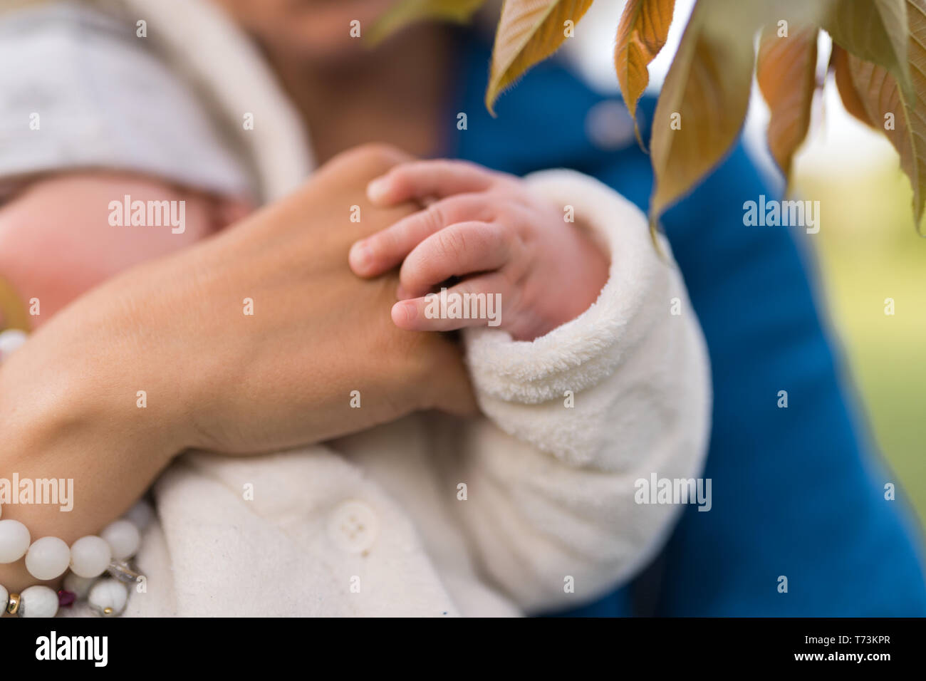Mani da vicino - giovane madre donna godendo di tempo libero con il suo bambino bambino bambino bambino bambino - bianco caucasico bambino con una mano del genitore visibile - vestito in bianco Foto Stock