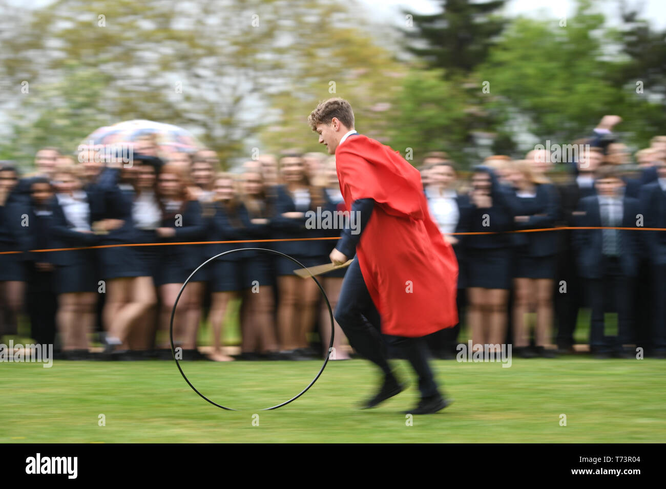 Gli studenti prendono parte all'annuale King's Ely Hoop Trundle sul prato Est a Ely Cathedral, per contrassegnare la rifondazione della scuola da parte di Re Enrico VIII nel 1541. Il corso è a 75 yard dash per un post e posteriore mentre bowling il cerchio con un bastone di legno. Foto Stock