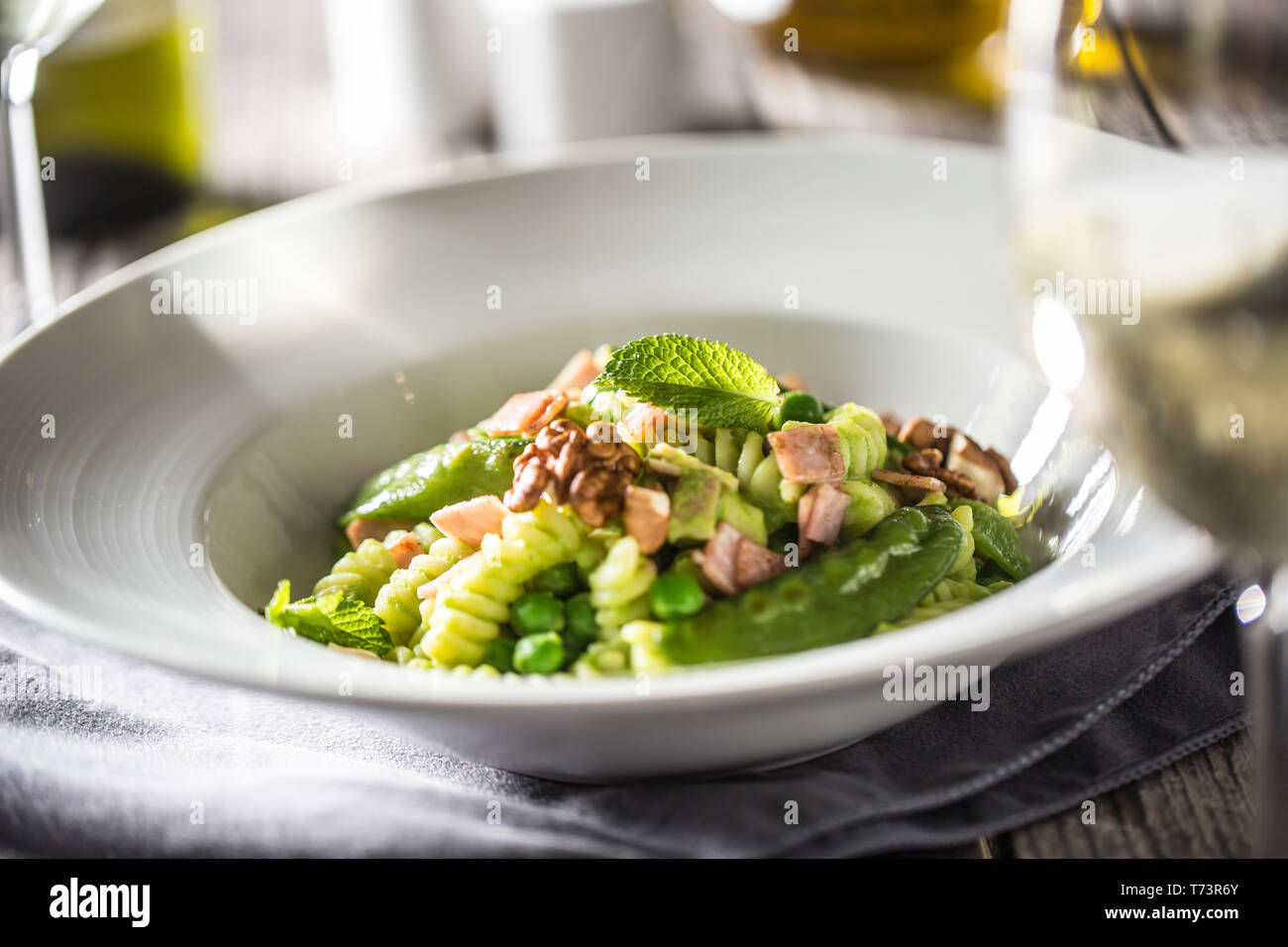 Fusilli con piselli verdi prosciutto noci con vino bianco. italiano o cucina mediterranea. Foto Stock