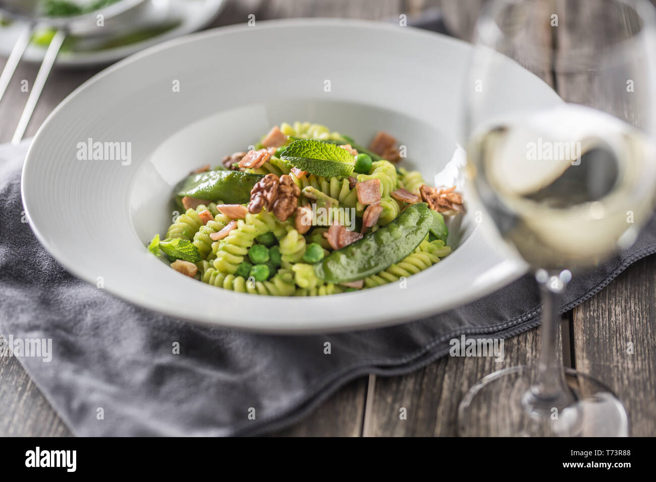 Fusilli con piselli verdi prosciutto noci con vino bianco. italiano o cucina mediterranea. Foto Stock