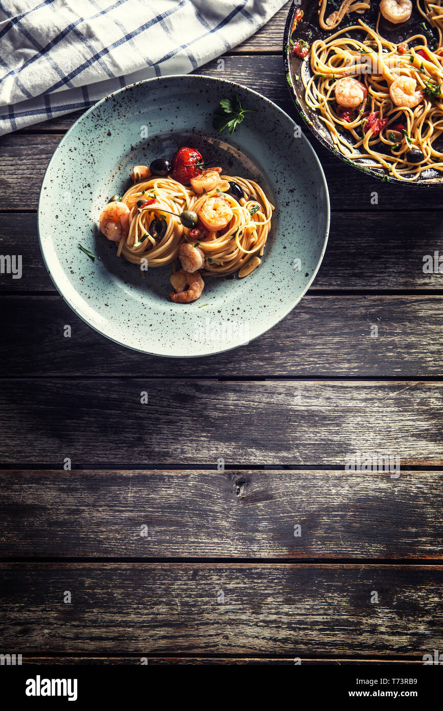 Spaghetti di pasta sulla piastra e pan di gamberi con salsa di pomodoro toatoes e erbe aromatiche. Italiano o cucina mediterranea. Foto Stock