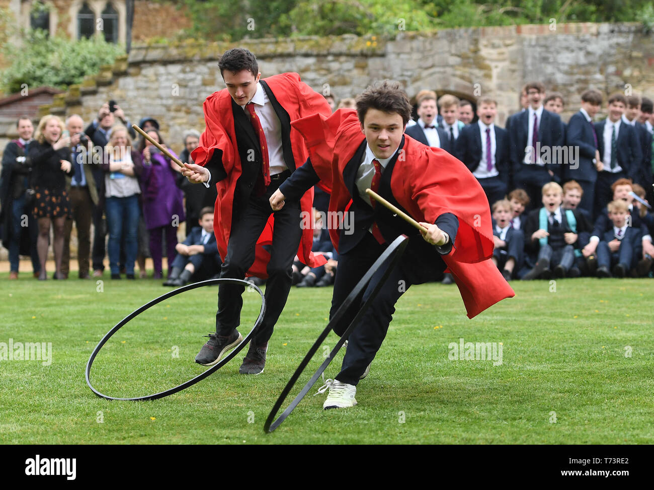 Gli studenti prendono parte all'annuale King's Ely Hoop Trundle sul prato Est a Ely Cathedral, per contrassegnare la rifondazione della scuola da parte di Re Enrico VIII nel 1541. Il corso è a 75 yard dash per un post e posteriore mentre bowling il cerchio con un bastone di legno. Foto Stock