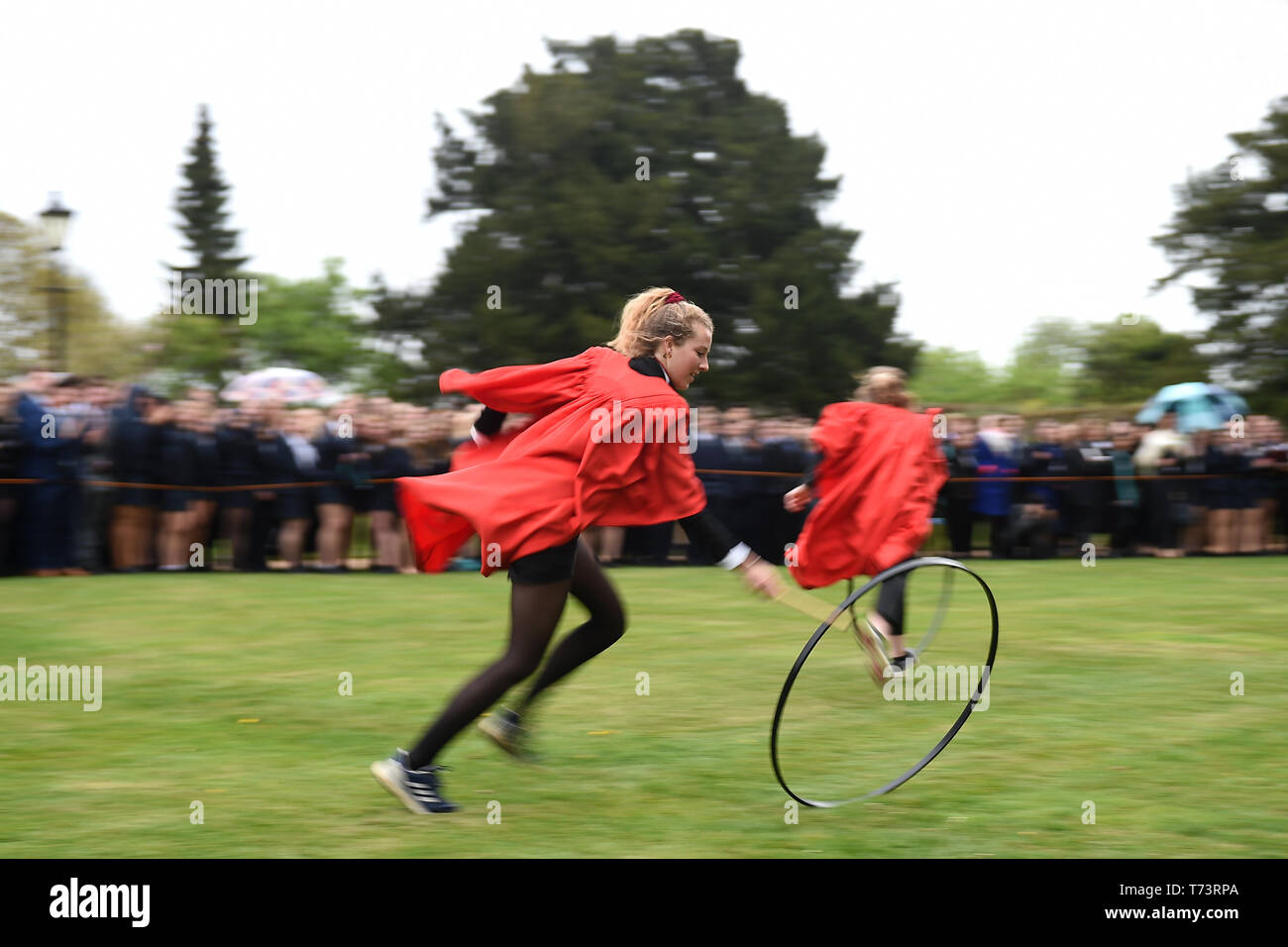 Gli studenti prendono parte all'annuale King's Ely Hoop Trundle sul prato Est a Ely Cathedral, per contrassegnare la rifondazione della scuola da parte di Re Enrico VIII nel 1541. Il corso è a 75 yard dash per un post e posteriore mentre bowling il cerchio con un bastone di legno. Foto Stock