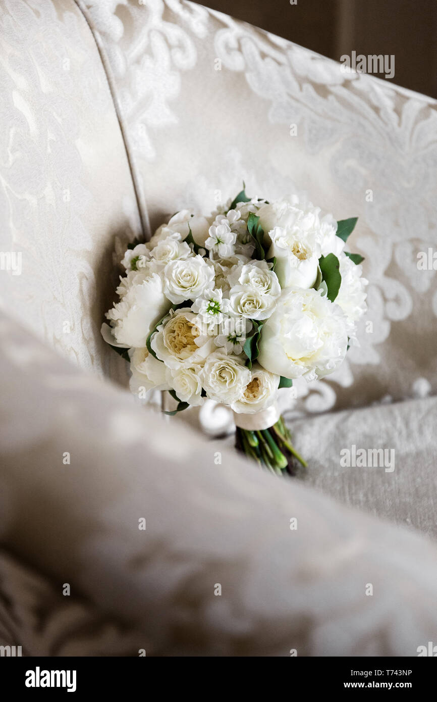 Raffinato bouquet di rose bianche con le peonie, contro lo sfondo di una poltrona Foto Stock