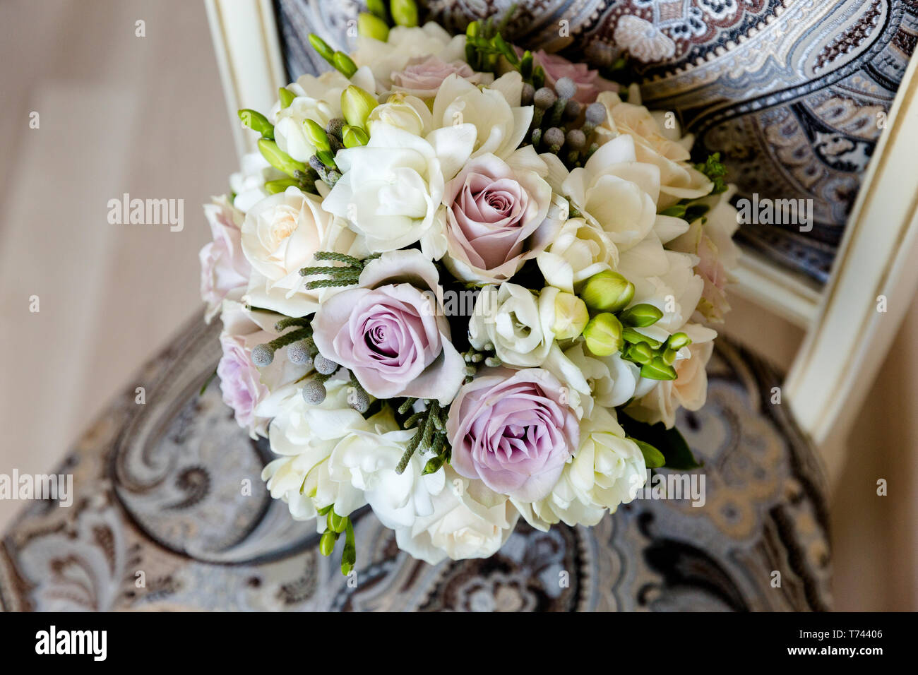 Le gemme di colore bianco e grigio rose in combinazione con un bianco fresia in un mazzo di nozze su una sedia Foto Stock