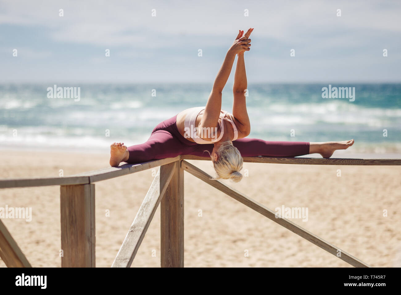 Caucasian donna bionda la pratica dello yoga in spiaggia Foto Stock