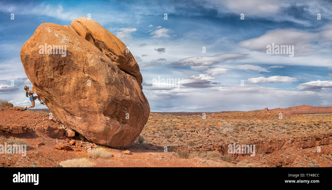 Una donna si blocca sul lato di boulder nella Valle degli Dèi; Utah, Stati Uniti d'America Foto Stock