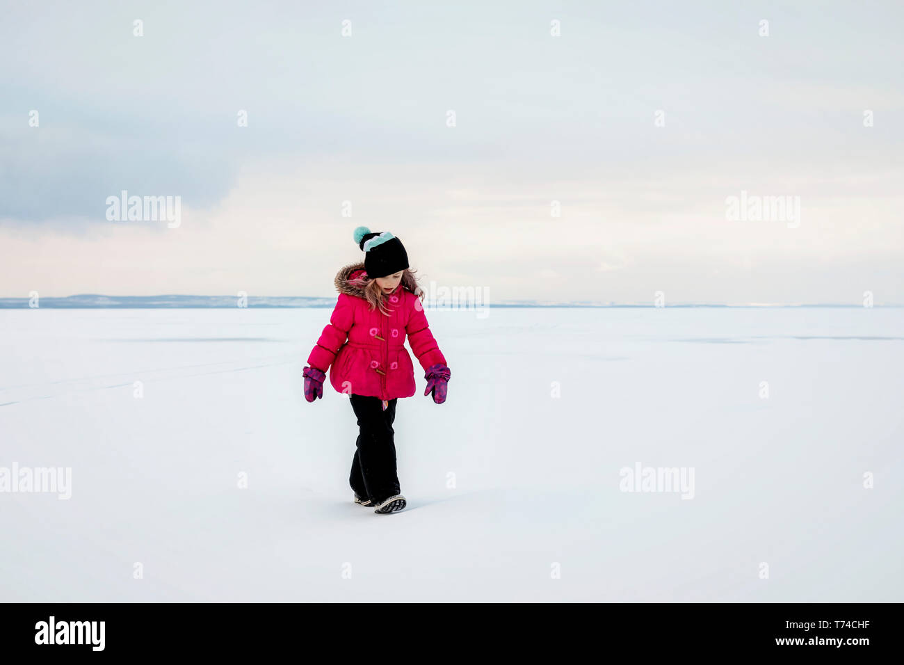 Una giovane ragazza camminare su un lago ghiacciato mentre la pesca sul ghiaccio durante un inverno una gita di famiglia sul Lago Wabamun: Wabamun, Alberta, Canada Foto Stock