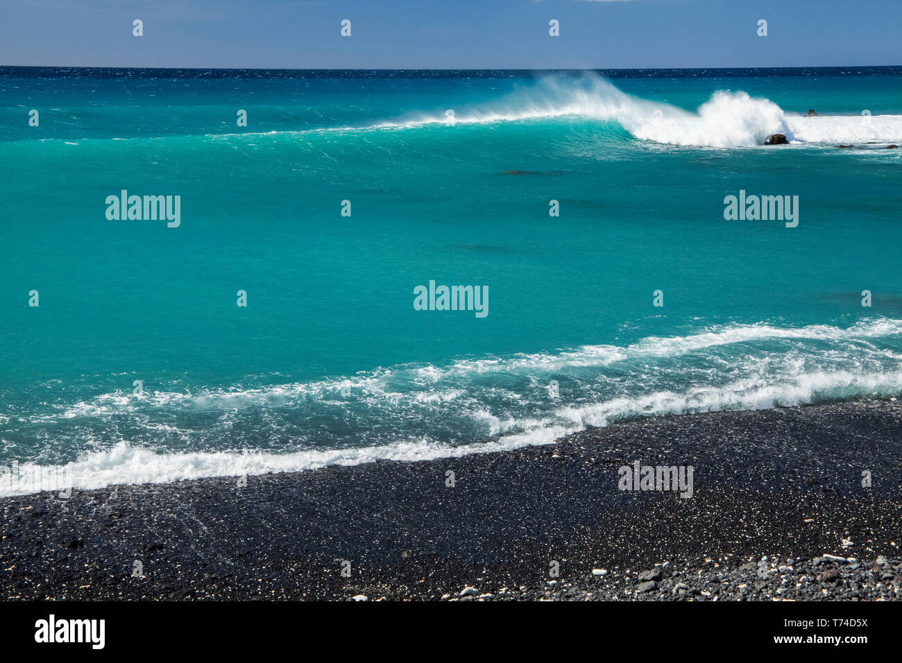 Il surf rompe sulla spiaggia di sabbia nera, Pueo Bay, a nord della costa di Kona; Kailua-Kona, isola di Hawaii, Hawaii, Stati Uniti d'America Foto Stock
