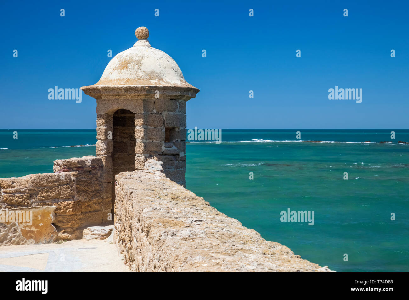 Muro di pietra e la torre che guarda al Mare Mediterraneo; Cadice, Andalusia, Spagna Foto Stock