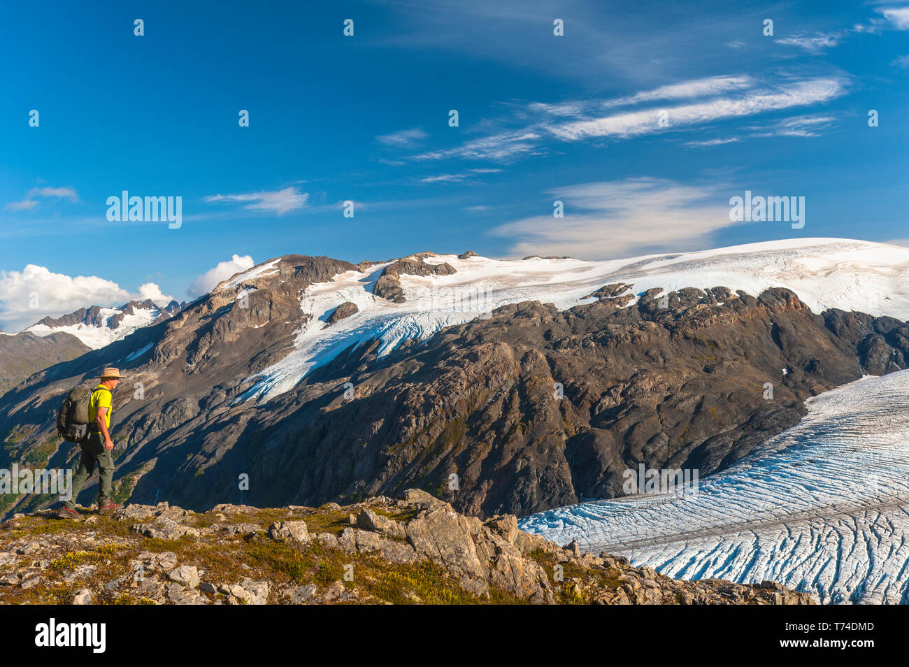 Un uomo a piedi vicino al Harding Icefield Trail con i monti Kenai e un ghiacciaio senza nome sospeso in background, Kenai Fjords National Park,... Foto Stock