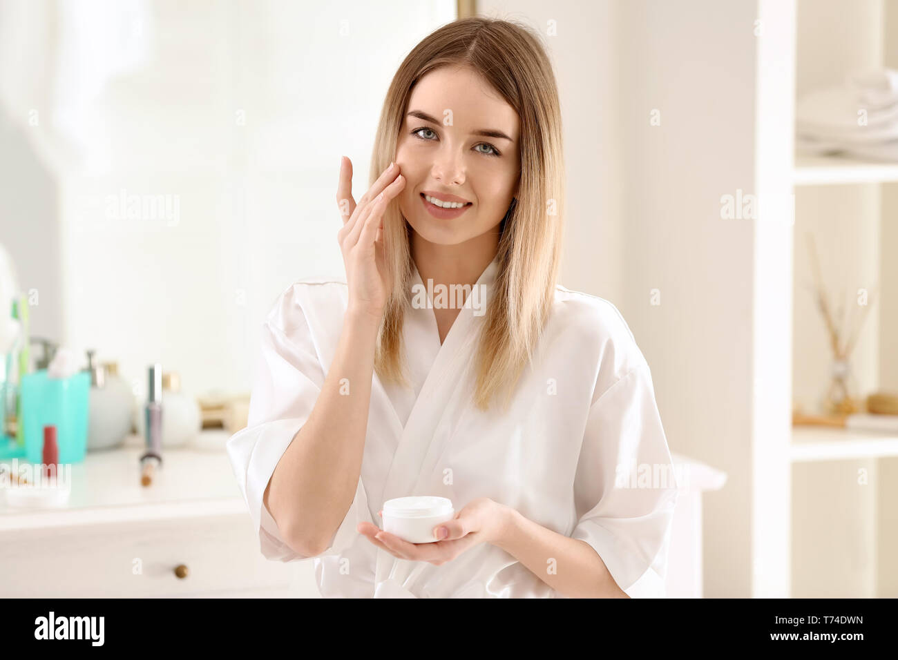 Bella giovane donna di applicare la crema al mattino Foto Stock