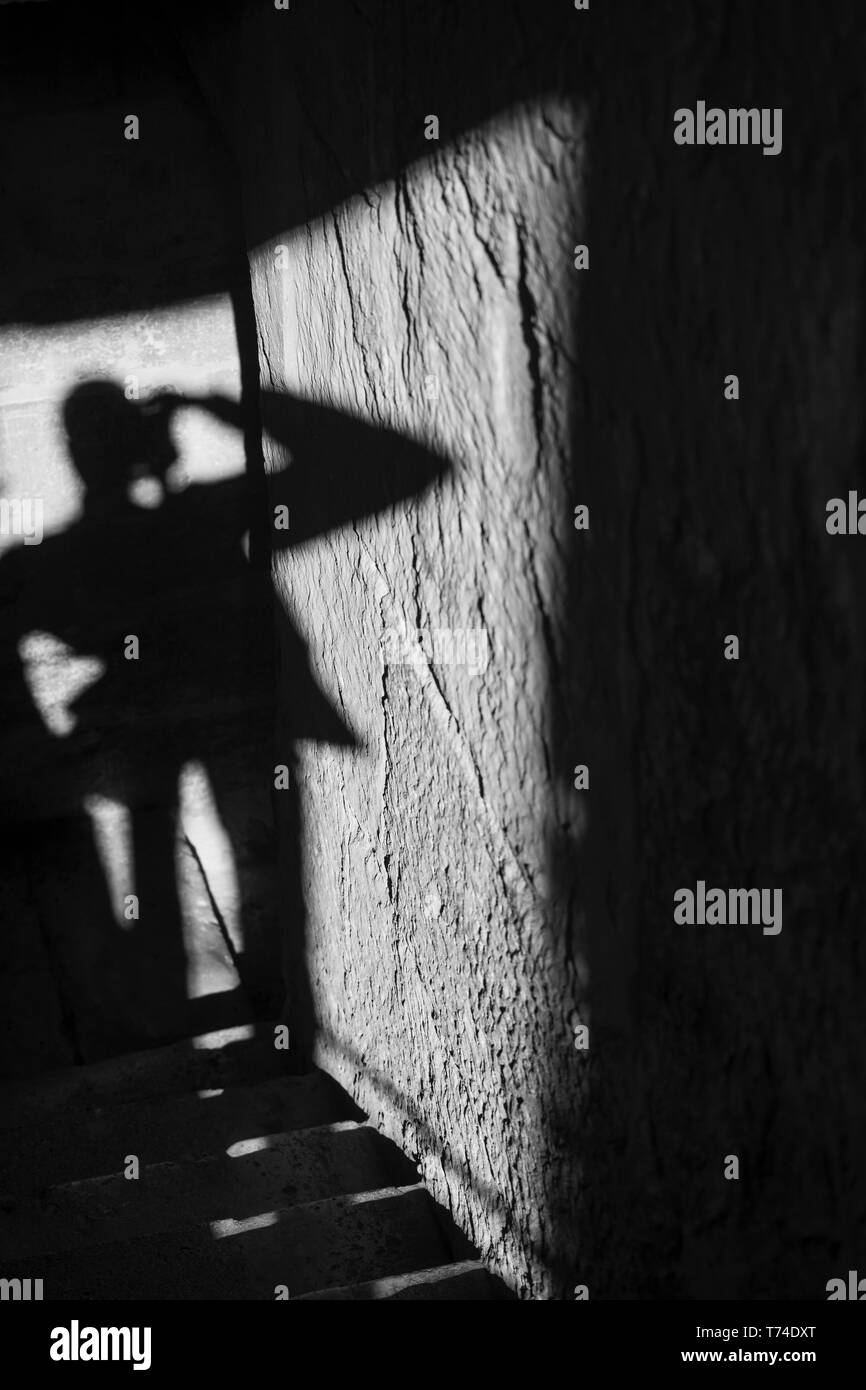Ombra di un turista e permanente di scattare una foto con la luce del sole e le ombre proiettate sul muro e passaggi; Cordoba, in provincia di Cordoba, Spagna Foto Stock