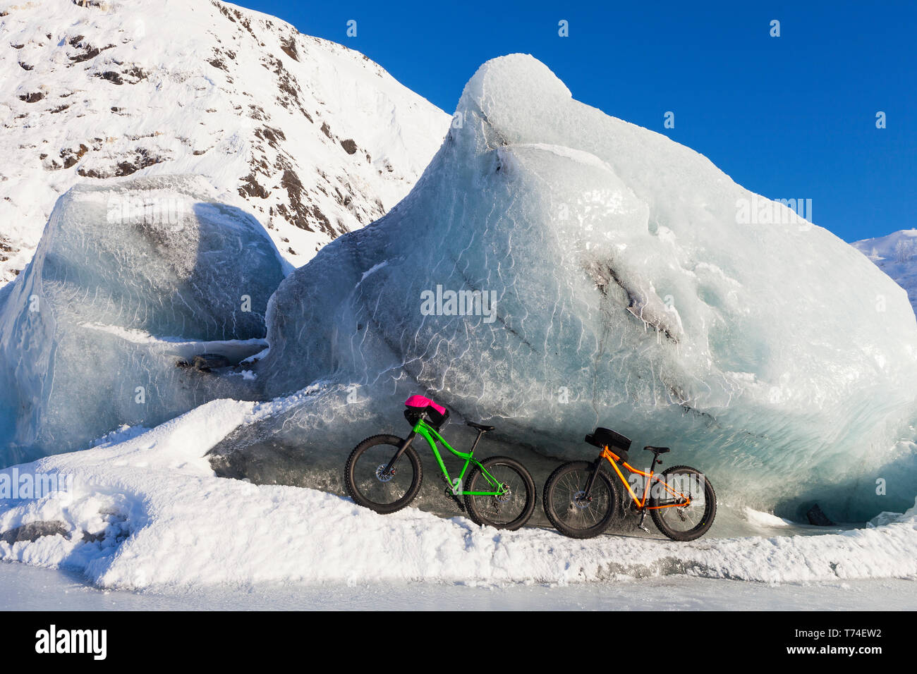 Fatbikes, 907 Fat Tire Bike e preparate un battuto di lardo Fat Tire Bike, in appoggio contro il gigantesco iceberg in inverno sul lago di Portage, Chugach National Forest Foto Stock