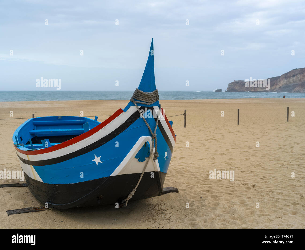 Una colorata e canotto in legno sulla spiaggia della località balneare di Nazare; Nazare, Distretto di Leiria, Portogallo Foto Stock