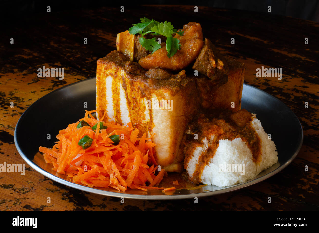Un coniglietto di Durban Chow - o, in questo caso un quarto di montone bunny - servita con sambals. Questo è un iconico Durban pasto composto da una sezione di una forma di pane Foto Stock