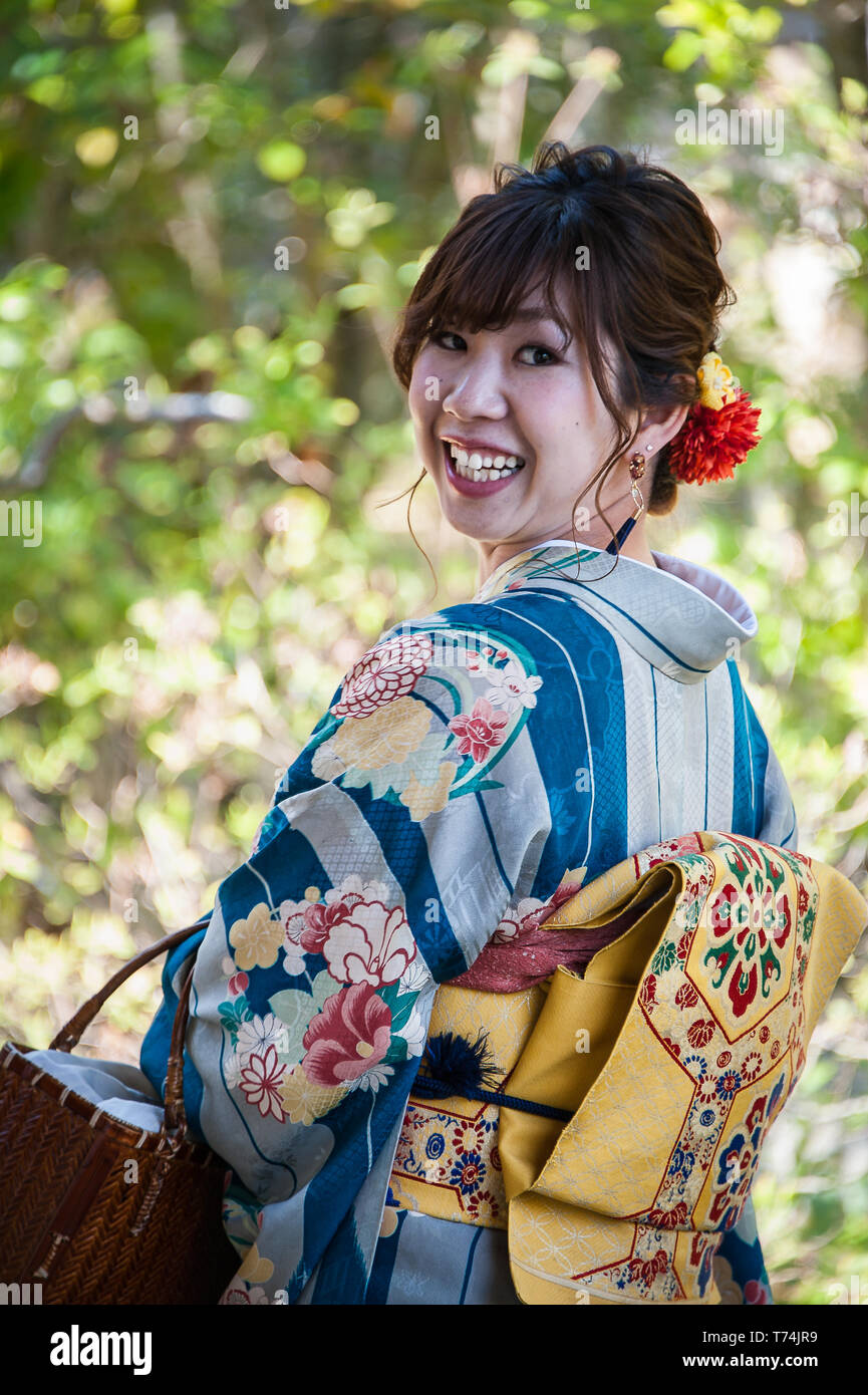 Kyoto, Giappone - Aprile 2019: Ritratto di ragazza sorridente indossa bellissimi Kimono guardando indietro sopra la sua spalla Foto Stock