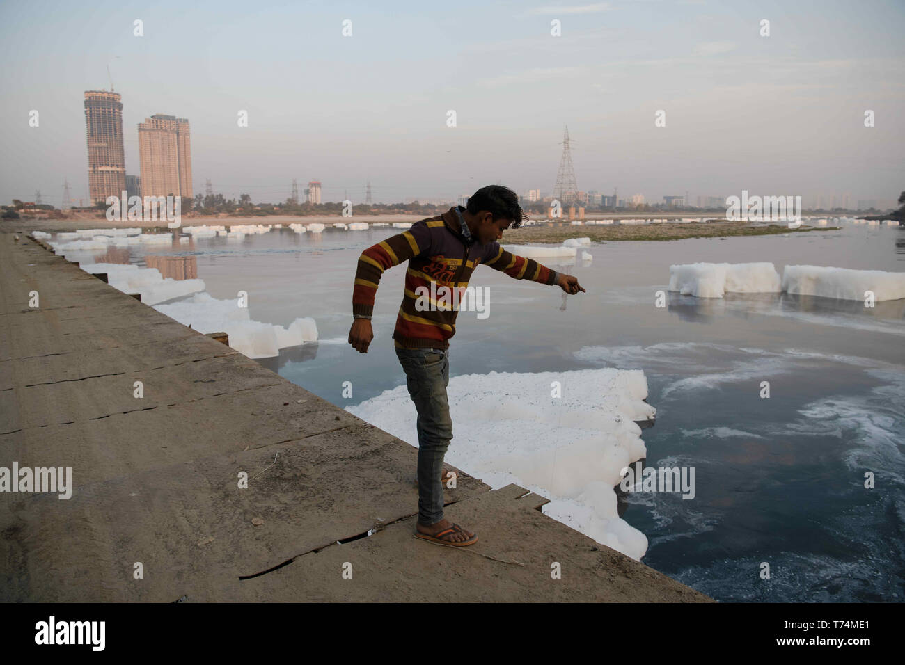 New Delhi, Delhi, India. Decimo gen, 2019. I pescatori locali si vede la pesca al fiume Yamuna coperto dalla schiuma da scarico di industriali non trattati e rifiuti domestici.fiume Yamuna, spesso chiamato Delhi's lifeline, è stato etichettato come "ecologicamente morti'' per la sua apparente incapacità di riconquistare la sua limpidezza iniziale. Yamuna è traboccante di schiuma come il risultato di industriali non trattati e rifiuti domestici scarico nel fiume. Il drastico calo del livello di ossigeno è responsabile per l'uccisione di varie specie e di danneggiare la ecologia. Questa è anche una minaccia economica per i pescatori. (Cred Foto Stock