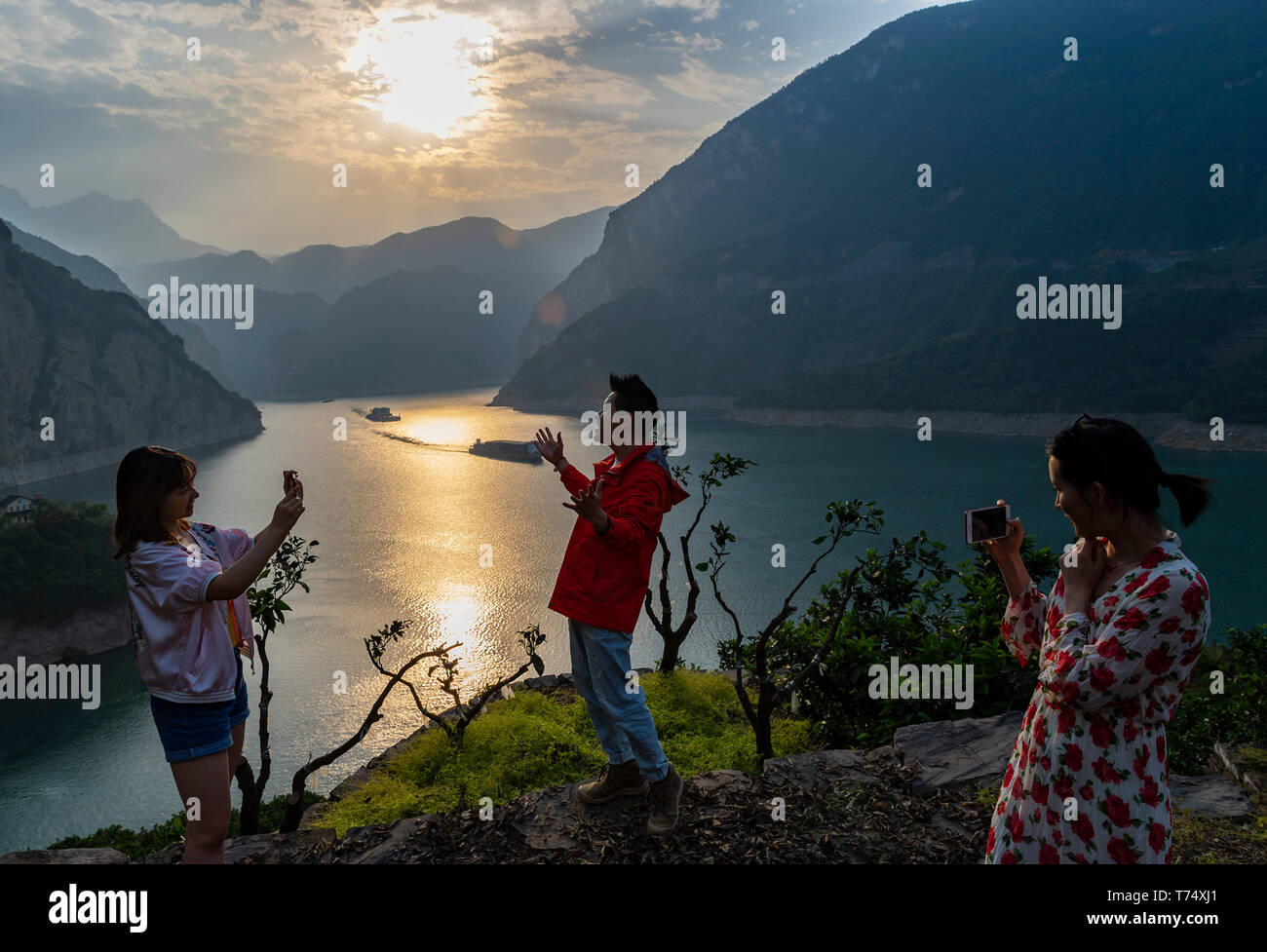 (190504) -- YICHANG, 4 maggio 2019 (Xinhua) -- Zheng Yunbo (C) canta come sua moglie (1R) e un business partner girare dei video per il caricamento da parte del fiume Yangtze in Cina centrale della provincia di Hubei, 3 maggio 2019. Zheng Yunbo, 32, ha iniziato la sua carriera come un coltivatore di frutta nella sua casa di città, Zigui County nel 2012 quando ha abbandonato il suo lavoro in una grande città diversi anni dopo la laurea da Wuhan Conservatorio di Musica. Oltre all agricoltura, ha preso i vantaggi della sua specialità per il caricamento di video musicali su reti sociali per promuovere i frutti che egli crebbe su oltre 100 um (circa 6,67 ettari) della locazione di campi. I video in modo Foto Stock