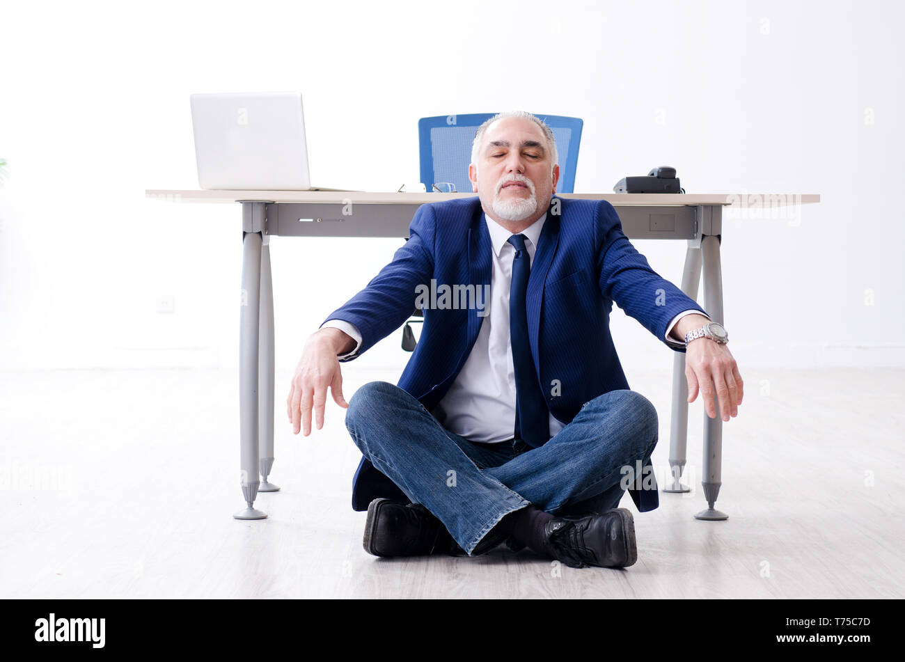 Imprenditore invecchiato facendo esercizi yoga in ufficio Foto Stock