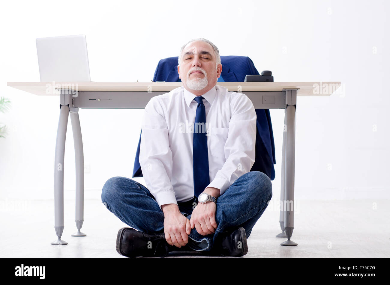 Imprenditore invecchiato facendo esercizi yoga in ufficio Foto Stock