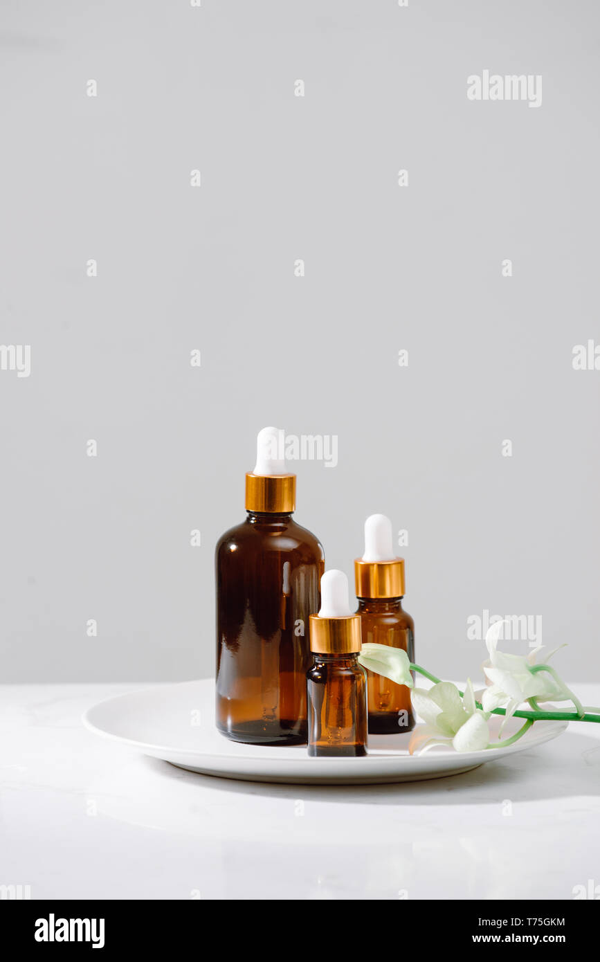 Impostazione di Spa con orchidee e olio essenziale in una bottiglia di vetro, aromaterapia concept Foto Stock