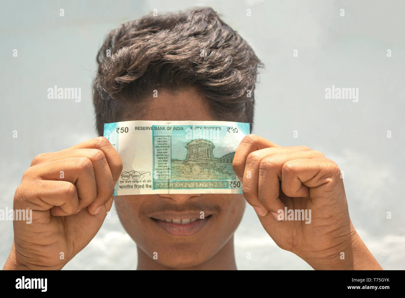 Un uomo si copre il viso con le bollette di denaro Foto Stock