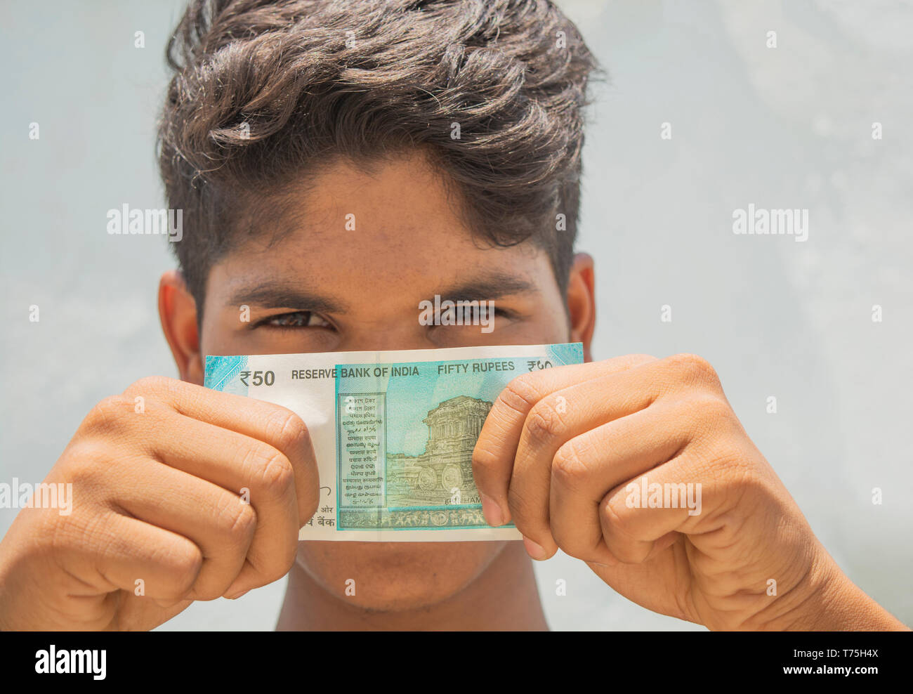 Un uomo si copre il viso con le bollette di denaro Foto Stock