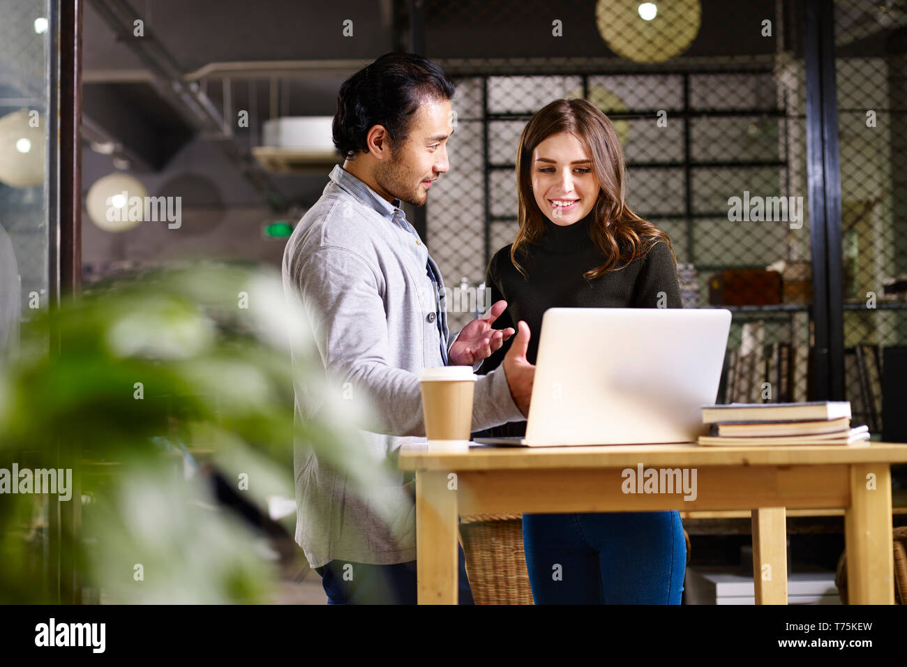 Asian business man e caucasico business donna avente una discussione in ufficio utilizzando il computer portatile. Foto Stock